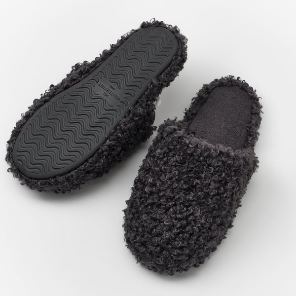 Black, curly slippers with grippy soles, designed for comfortable walking with support.