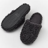 Black, curly slippers with grippy soles, designed for comfortable walking with support.
