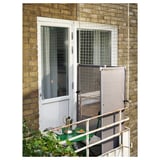 Small balcony with green table and chair, white door, YTTERSKÄR screen, plant.