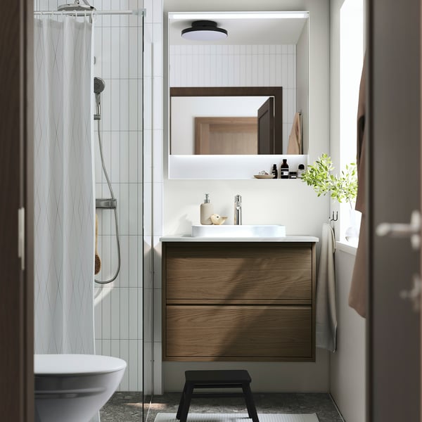 Baño moderno: mueble de madera con lavabo marrón, encimera blanca, espejo; Elegante, minimalista.