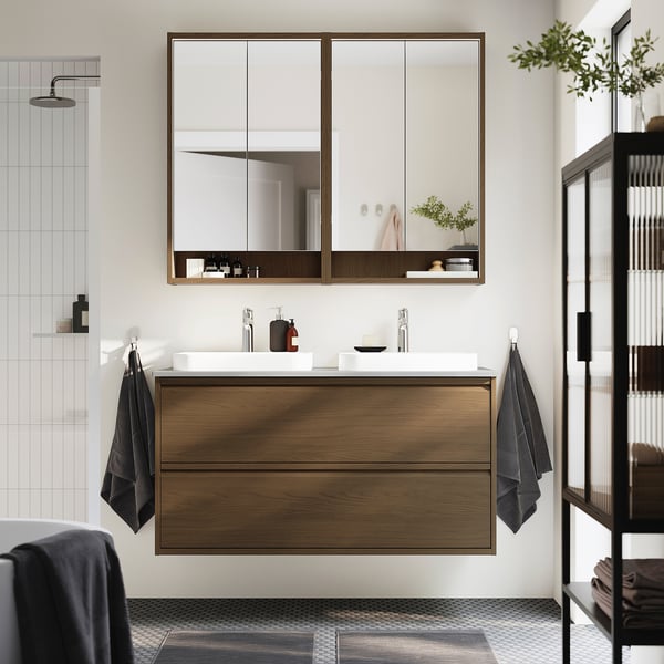 Baño moderno con tocador flotante de roble, lavabos de mármol, gabinete con espejo y ducha con azulejos.