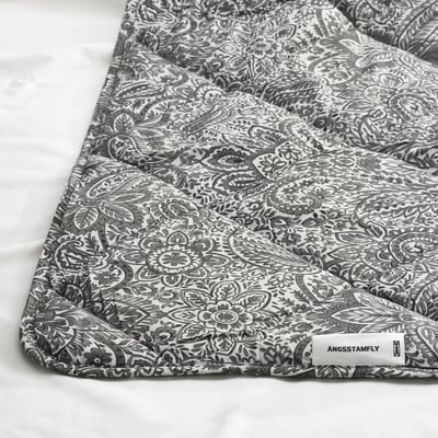 El edredón nórdico ÄNGSSTAMFLY es de color gris con motivos florales blancos, rectangular, y está fabricado en poliéster y algodón reciclados.