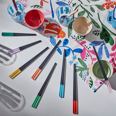 Palillos coloridos de diferentes longitudes sobre un mantel floral, adecuados tanto para adultos como para niños.
