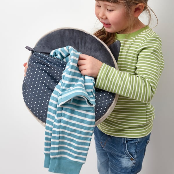 Niña pequeña que sostiene una almohada suave en forma de gato con bolsillo oculto, perfecta para guardar pijamas.