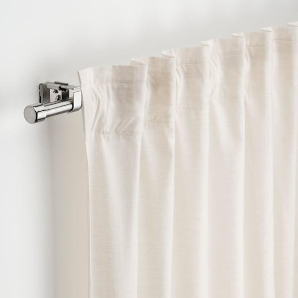 Cortina blanca sobre varilla de plata con soportes de pared, que muestra parte del conjunto BEKRÄFTA.
