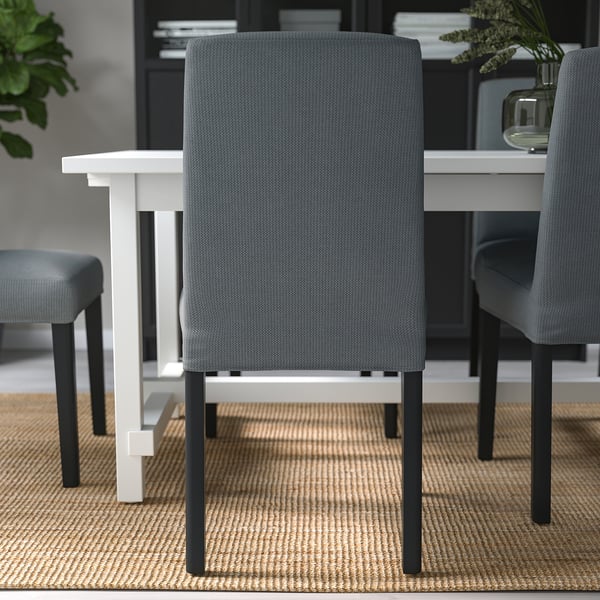 Múltiples sillas de comedor tapizadas alrededor de una mesa, tela gris con patas negras, adecuadas para una comodidad óptima al sentarse.