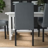 Múltiples sillas de comedor tapizadas alrededor de una mesa, tela gris con patas negras, adecuadas para una comodidad óptima al sentarse.