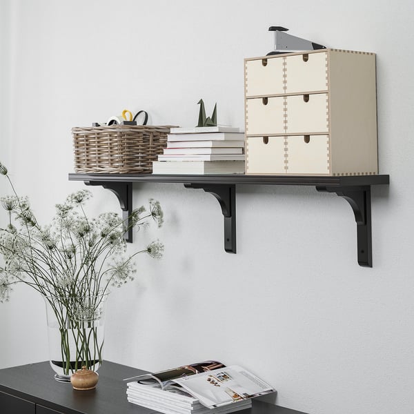 Estante de pared que muestra cajas de almacenamiento, cesta de mimbre, libros y artículos decorativos.