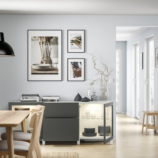 Comedor minimalista con mesa de madera clara, aparador gris, láminas artísticas.