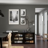 Aparador BESTÅ con platos, tazas, decoración y fotos sobre una pared gris.