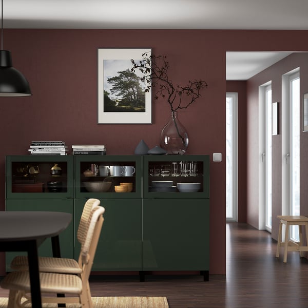 Aparador BESTÅ con vajilla, arte, jarrón y ramas. Cerca de la mesa de comedor, el pasillo y las puertas.