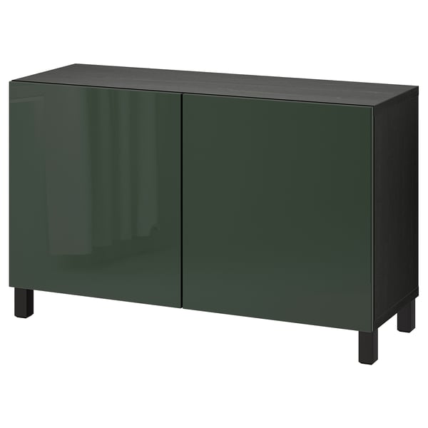 Un aparador BESTÅ verde oliva con dos puertas de cristal. Forma rectangular, cuatro patas, diseño moderno.