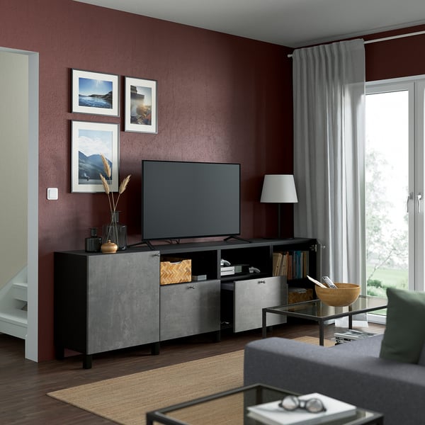 Sala de estar granate con banco de tv BESTÅ, estantes, cajones y cortinas ajustables.