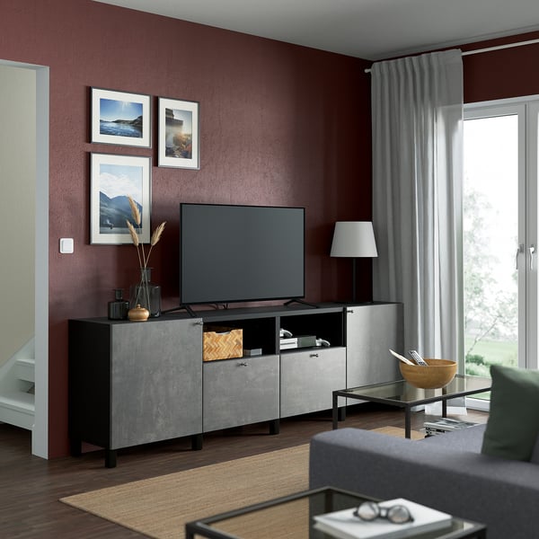 Sala de estar moderna con tv en la unidad BESTÅ contra la pared de color burdeos. Cerca de mesa de centro y ventana con vistas.