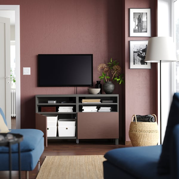 Sala de estar moderna con paredes granates, sofá azul, mueble de TV BESTÅ, lámpara y arte.