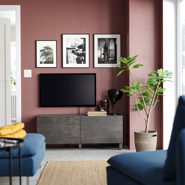 Sala de estar moderna con paredes marrones, muebles azules, mueble de TV gris, televisor de pantalla plana, lámpara negra, manta amarilla y planta grande.
