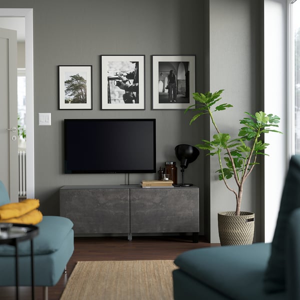Sala de estar moderna con paredes de color gris oscuro, con mueble de TV BESTÅ, sillas vegetales y verde azulado.