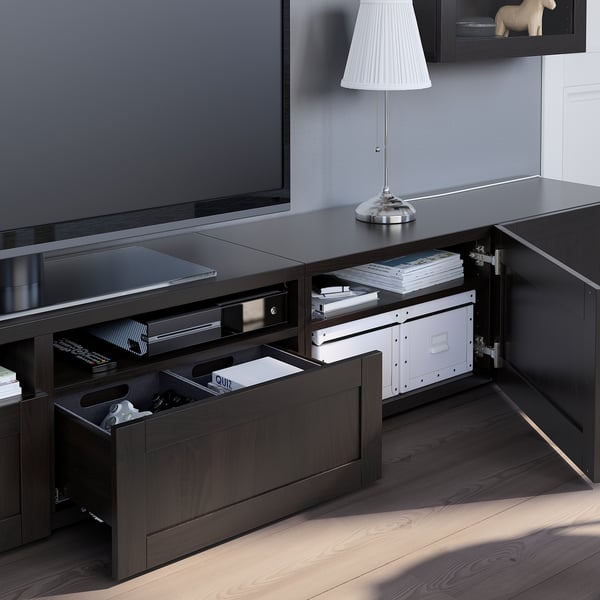 Mueble de TV de madera oscura con cajones abiertos, que muestra un almacenamiento organizado con una lámpara en la parte superior y un televisor de pantalla plana en la parte superior.