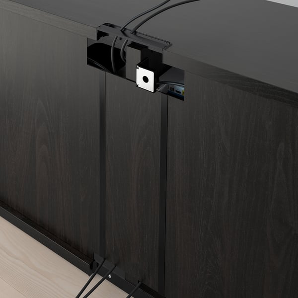 Mueble de tv negro con pies ajustables y gestión de cables. Los cables atraviesan las ranuras traseras, manteniéndolas ordenadas y accesibles.