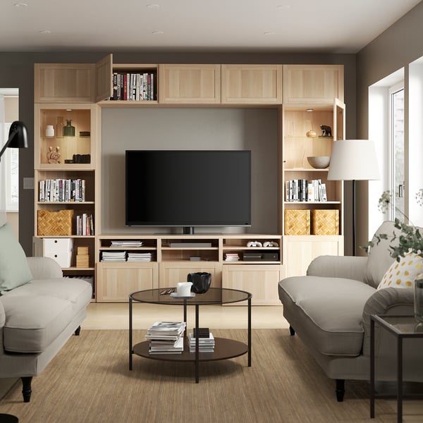 Sala de estar moderna con mueble de TV BESTÅ, sofás y mesa de centro de cristal.