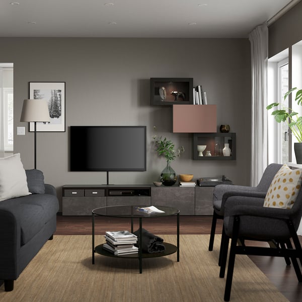Sala de estar moderna con paredes oscuras, mueble de TV BESTÅ, TV de pantalla plana, sofá gris, silla amarilla, mesa de cristal, lámpara de pie, gran ventana.