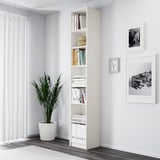 Habitación minimalista con librería blanca BILLY, planta alta y arte de pared.
