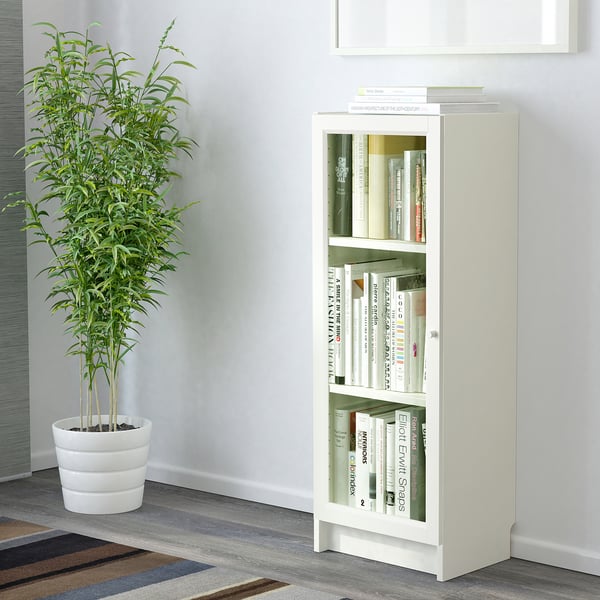 Librería BILLY con puertas de vidrio, libros y planta.