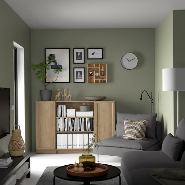 Sala de estar verde con sofá gris, estantería BILLY, reloj y mesa de café.