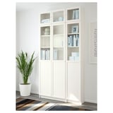 Librería BILLY blanca con puertas de cristal y paneles. Muestra libros y oculta el desorden. Anclado a la pared para mayor estabilidad.