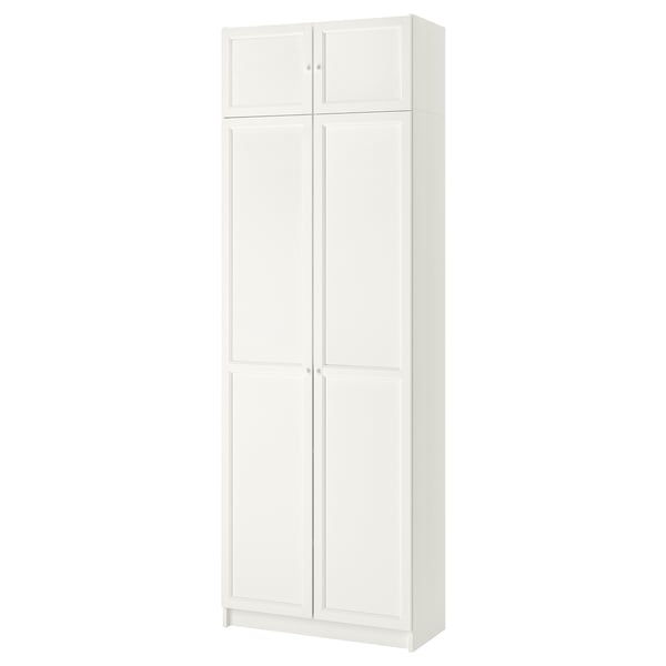 Librería BILLY blanca con 4 estantes ajustables detrás de puertas dobles.