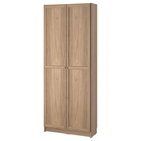 Una librería BILLY en color roble claro, fabricada en tableros de partículas y tableros de fibra, con dos puertas de panel y estantes ajustables para un almacenamiento libre de polvo.