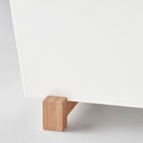 Un elegante soporte para plantas con patas de madera que soportan una superficie blanca y elegante, que destaca los materiales y el diseño de calidad.