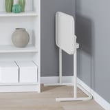 Soporte ajustable blanco para portátil contra pared gris, junto a estantes blancos con jarrones decorativos y compartimentos de almacenamiento.