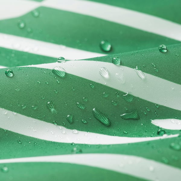 Cortina de ducha verde con gotas de agua, que luce su tejido repelente al agua.