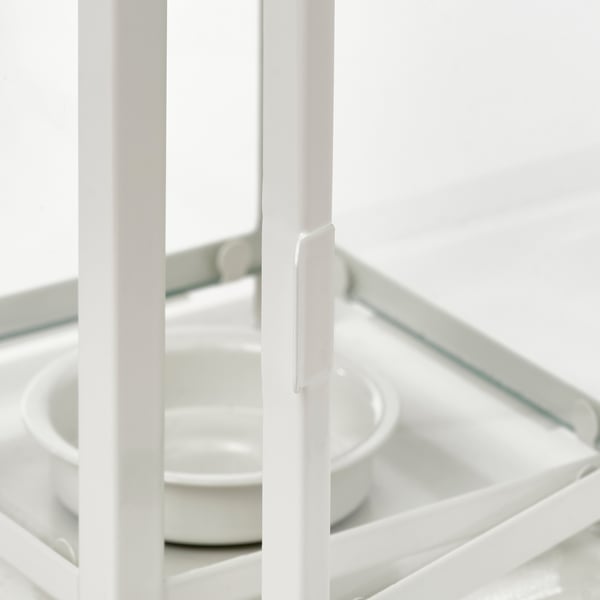 Linterna BORRBY totalmente blanca que sostiene varias velas pequeñas, que evocan comodidad. Tapa de vidrio y construcción de acero visible.