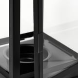 Linterna con marco de metal negro y paneles de vidrio transparente, que muestra artesanía de alta calidad y durabilidad.