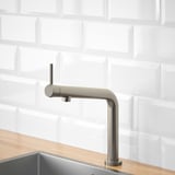 Grifo de cocina moderno con acabado en acero inoxidable, unido a la encimera de madera, enfatizando la eficiencia hídrica y energética.
