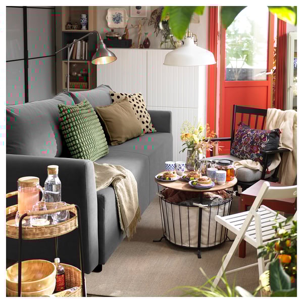 Sala de estar moderna con sofá BRISSUND gris, mesas de madera, almohadas estampadas y una decoración acogedora.