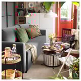Sala de estar moderna con sofá BRISSUND gris, mesas de madera, almohadas estampadas y una decoración acogedora.
