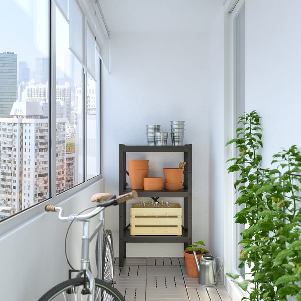 Balcón con almacenamiento de acero negro BOR, ollas de barro, bicicleta y vegetación contra la pared blanca.