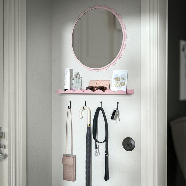Estantería rosa en la pared con espejo, perfume, gafas de sol y tarjeta motivacional sobre los ganchos con objetos colgantes, incluyendo bolsa, llaves y paraguas.