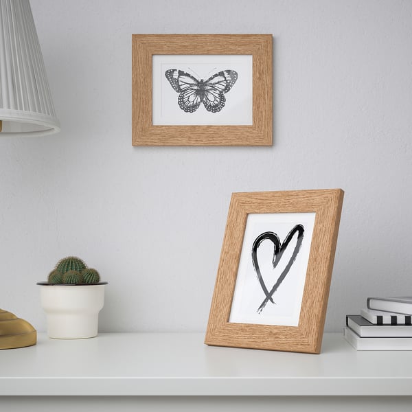 Marcos de madera: mariposa, corazón. Uno en la estantería con cactus, libros; uno cuelga.