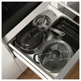 Cajón de cocina con ollas y sartenes, colores negro y plata, esmalte y acero inoxidable.