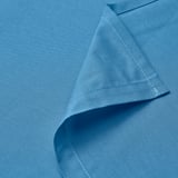 Sábana plana de algodón azul, cuidadosamente doblada. Bordes cosidos visibles, que muestran la artesanía de calidad.