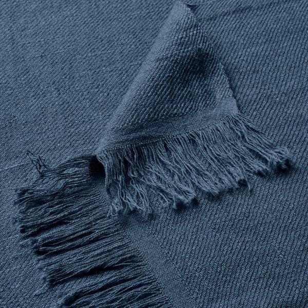 Manta texturizada en azul oscuro con bordes con flecos. Suave mezcla de lino y algodón, doblada cuidadosamente.