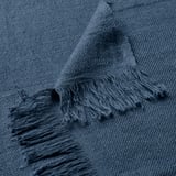 Manta texturizada en azul oscuro con bordes con flecos. Suave mezcla de lino y algodón, doblada cuidadosamente.