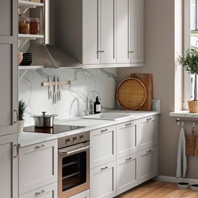 Encimera de cocina blanca moderna con estufa, horno, placa para salpicaduras de mármol y fregadero grande.