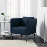 Sillón azul con cojín de respaldo ajustable, reposapiés y lámpara de pie alta a su lado.