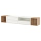 Estantería moderna montada en la pared, llamada EKET, blanca con detalles en madera natural, que combina almacenamiento abierto y cerrado con un diseño elegante.