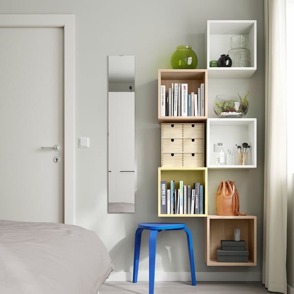 Dormitorio moderno con estantes EKET, decoración colorida y acentos vibrantes.